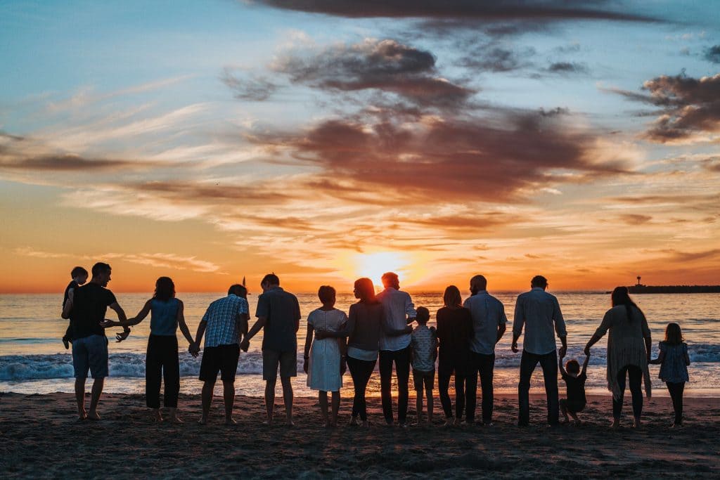 A family standing together at the beach during sunset